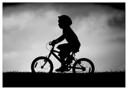 Postcard of cycling boy with coming storm. Photograph by Jolyon Yates